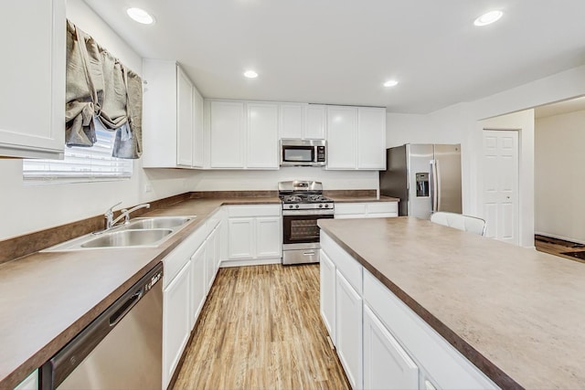 kitchen featuring white cabinets, appliances with stainless steel finishes, light wood-type flooring, and sink