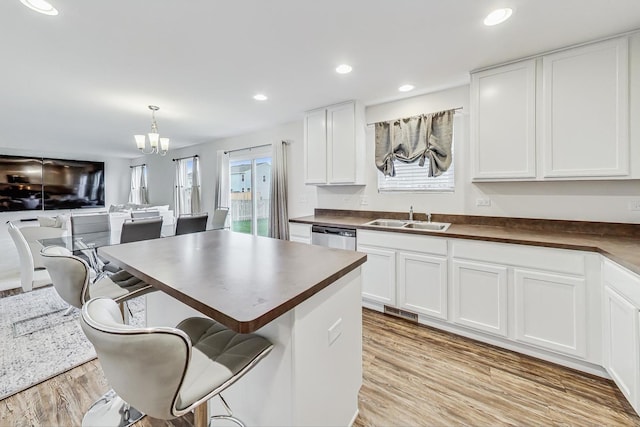 kitchen with light hardwood / wood-style floors, white cabinetry, a wealth of natural light, and sink