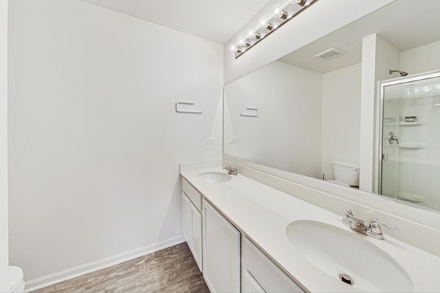 bathroom featuring wood-type flooring, vanity, toilet, and a shower with door