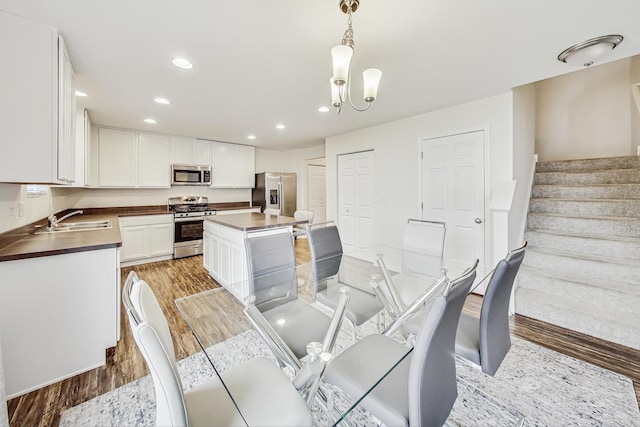 dining space featuring light wood-type flooring, an inviting chandelier, and sink