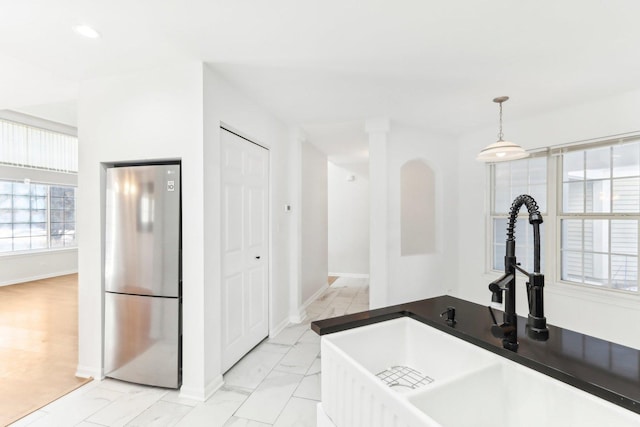 kitchen featuring sink, stainless steel refrigerator, and hanging light fixtures