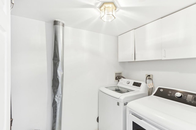 washroom with washer and dryer and cabinets