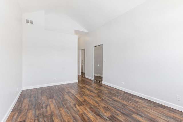 spare room featuring dark hardwood / wood-style flooring and high vaulted ceiling