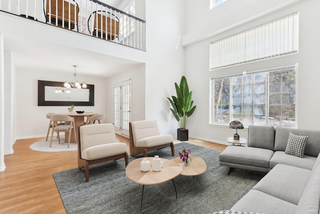 living room with an inviting chandelier, a towering ceiling, and wood-type flooring