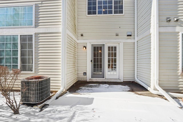 snow covered property entrance featuring central air condition unit