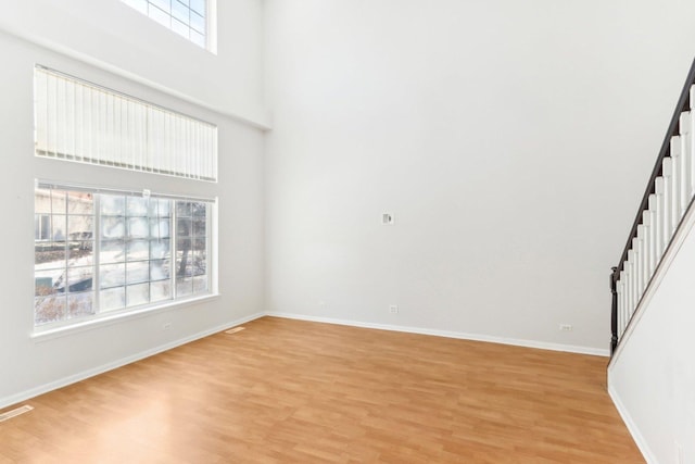 unfurnished living room featuring a towering ceiling and light wood-type flooring