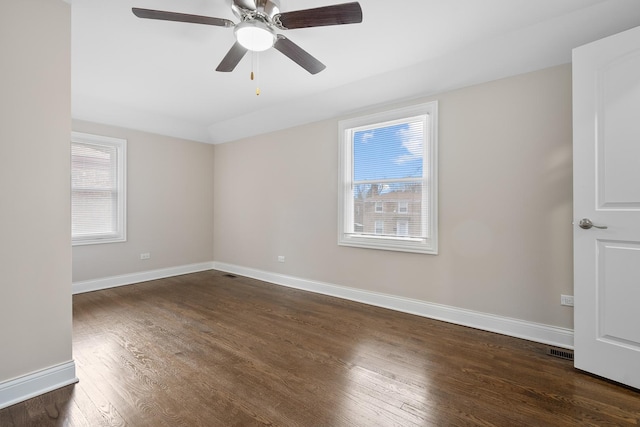 empty room with dark wood-type flooring, ceiling fan, and a healthy amount of sunlight
