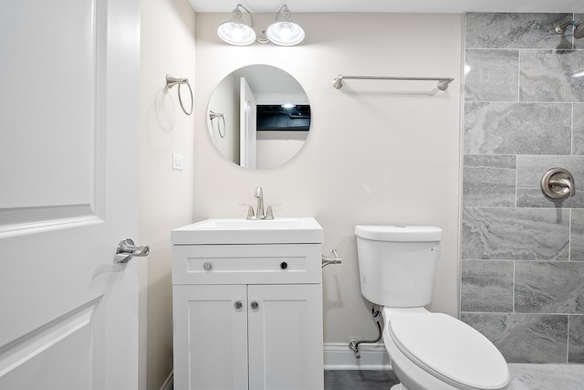 bathroom with vanity, toilet, and tiled shower