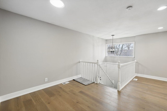 stairs featuring hardwood / wood-style floors and an inviting chandelier