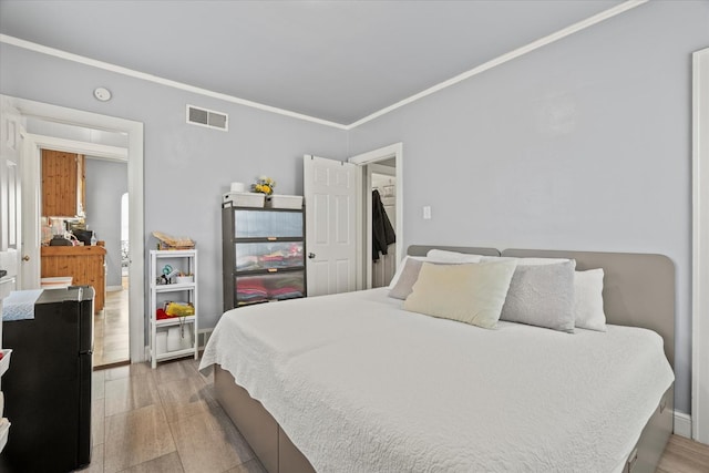 bedroom with light hardwood / wood-style floors and ornamental molding