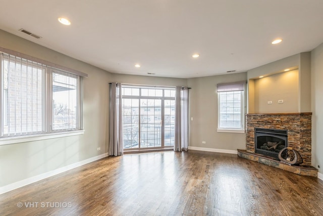 unfurnished living room featuring hardwood / wood-style flooring and a stone fireplace