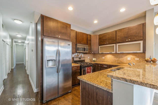 kitchen with kitchen peninsula, light stone countertops, sink, and stainless steel appliances