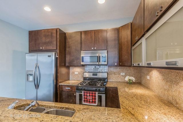 kitchen featuring light stone countertops, tasteful backsplash, dark brown cabinetry, stainless steel appliances, and sink