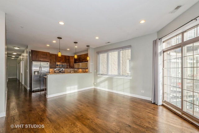 kitchen featuring decorative backsplash, light stone counters, appliances with stainless steel finishes, decorative light fixtures, and dark hardwood / wood-style flooring