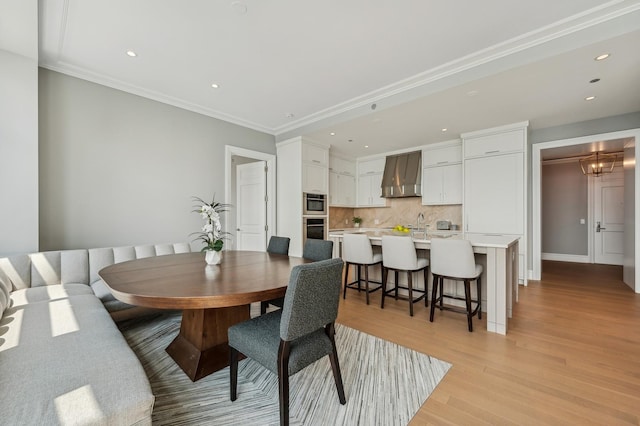 dining area with a water view, crown molding, and light hardwood / wood-style floors