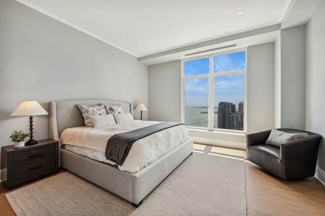 bedroom featuring connected bathroom, hardwood / wood-style flooring, ornamental molding, and electric panel