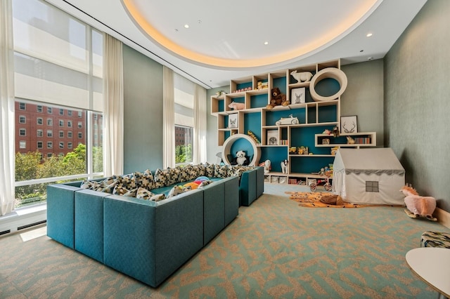 game room featuring a tray ceiling and carpet flooring