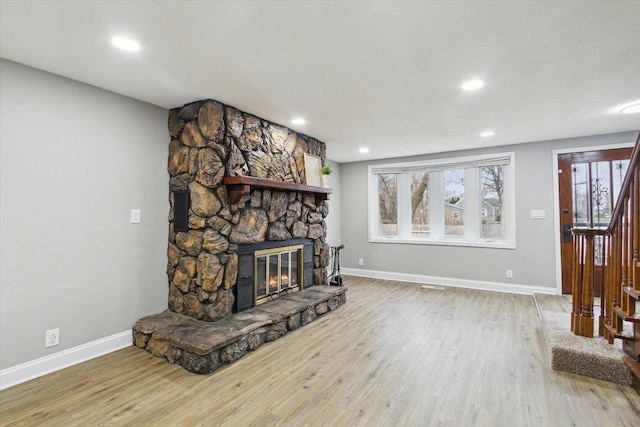 living room with hardwood / wood-style floors and a stone fireplace