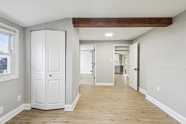 hallway with beam ceiling and light wood-type flooring