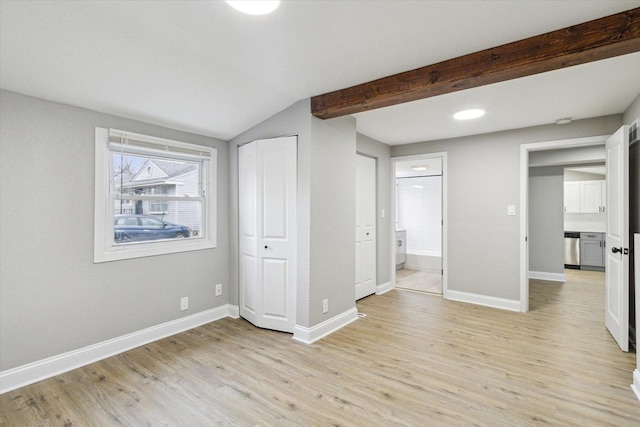 unfurnished bedroom with connected bathroom, lofted ceiling with beams, and light hardwood / wood-style flooring