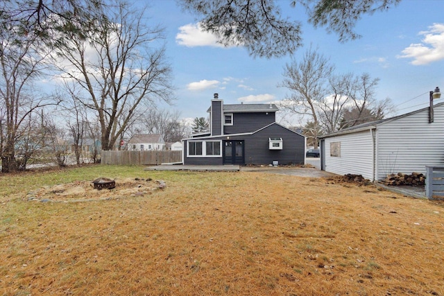 back of property with a sunroom, a yard, and an outdoor fire pit