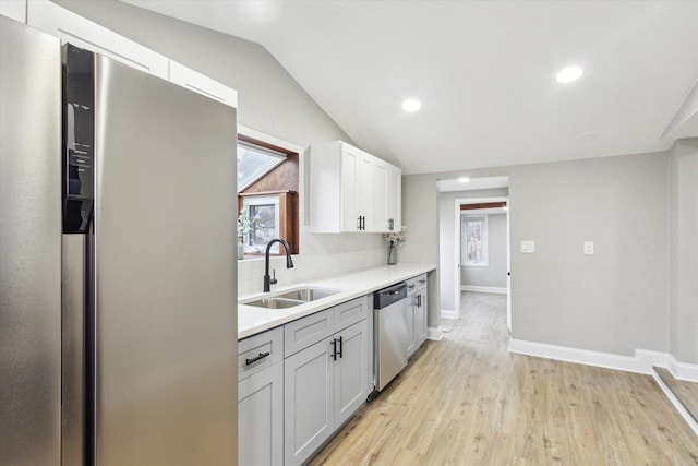 kitchen with lofted ceiling, white cabinets, sink, decorative backsplash, and stainless steel appliances