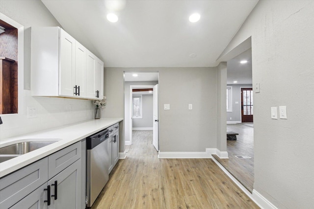 kitchen with dishwasher, sink, tasteful backsplash, light hardwood / wood-style floors, and white cabinetry