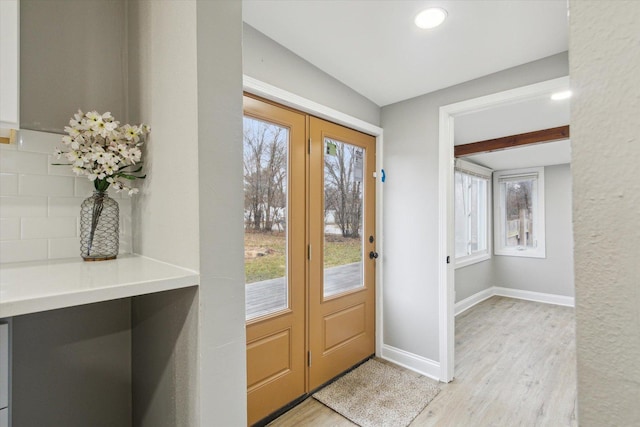 entrance foyer with beam ceiling, a wealth of natural light, and light wood-type flooring