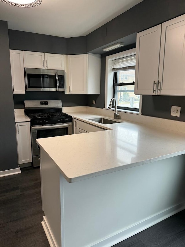 kitchen with kitchen peninsula, stainless steel appliances, white cabinetry, and sink