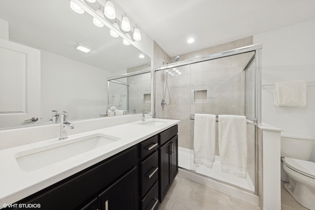 bathroom featuring tile patterned flooring, vanity, a shower with door, and toilet