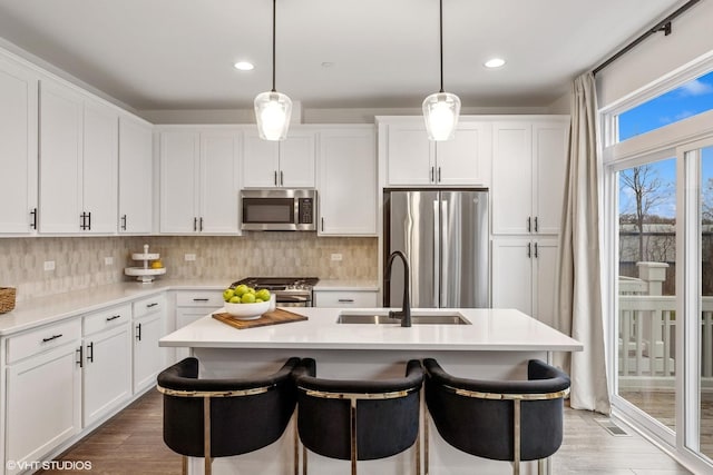 kitchen with sink, white cabinets, hanging light fixtures, and appliances with stainless steel finishes