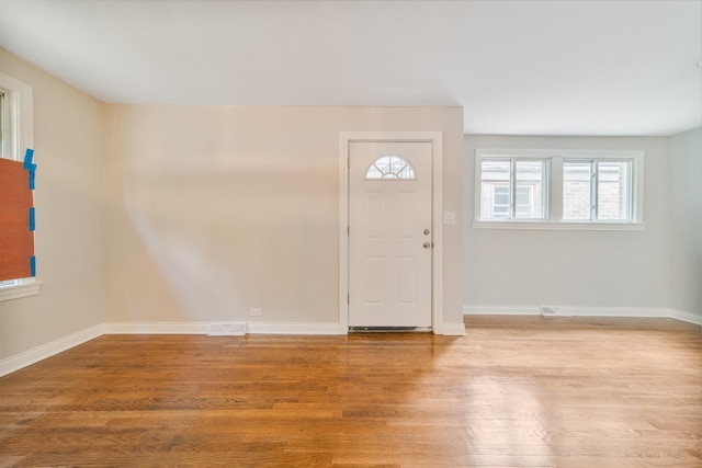 foyer entrance with light wood-type flooring, baseboards, and visible vents