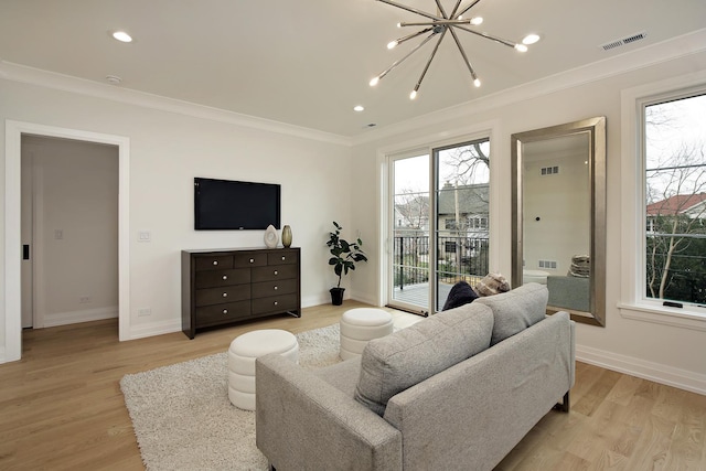 living room with crown molding, light hardwood / wood-style floors, and an inviting chandelier