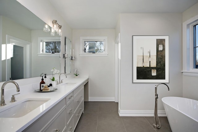 bathroom with a washtub, vanity, tile patterned floors, and a wealth of natural light