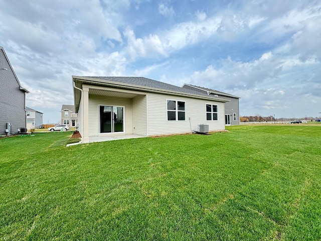 rear view of property with a lawn, central AC, and a patio area