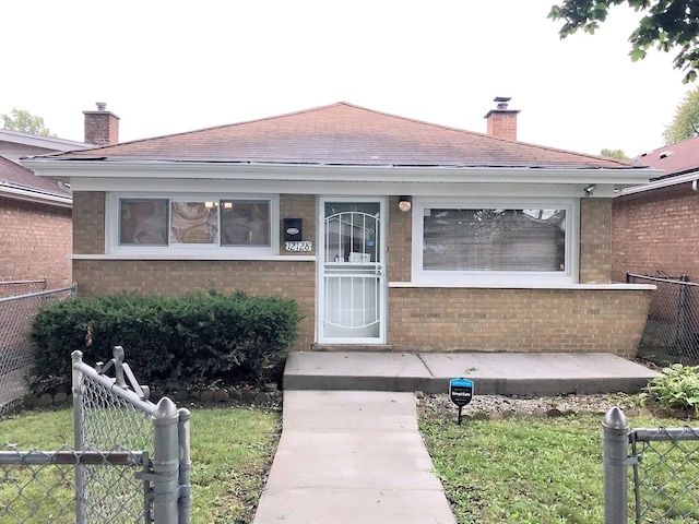 property entrance featuring a chimney, fence, and brick siding