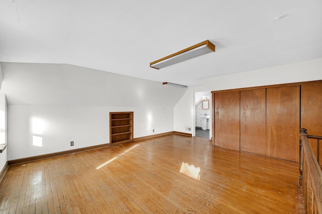 bonus room with lofted ceiling and light wood-type flooring