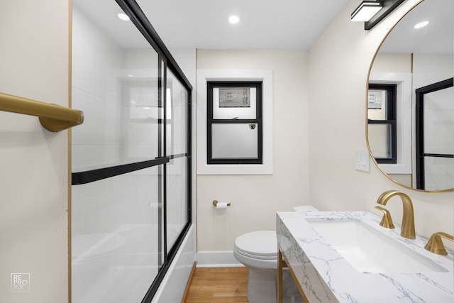 full bathroom with toilet, vanity, combined bath / shower with glass door, and hardwood / wood-style flooring