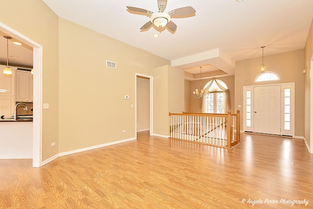 entrance foyer featuring light hardwood / wood-style flooring, ceiling fan with notable chandelier, and sink