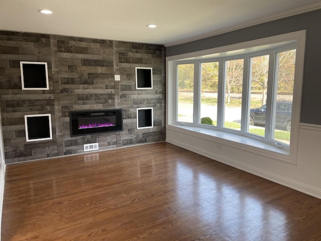 unfurnished living room featuring crown molding, a fireplace, and dark wood-type flooring