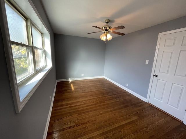 empty room with ceiling fan and dark wood-type flooring