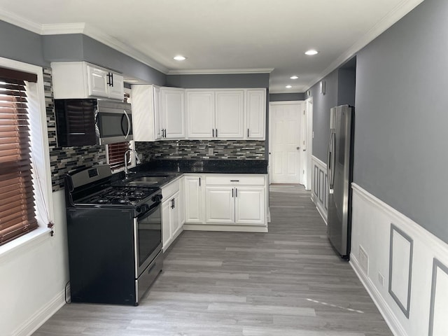 kitchen with sink, stainless steel appliances, light hardwood / wood-style flooring, decorative backsplash, and white cabinets