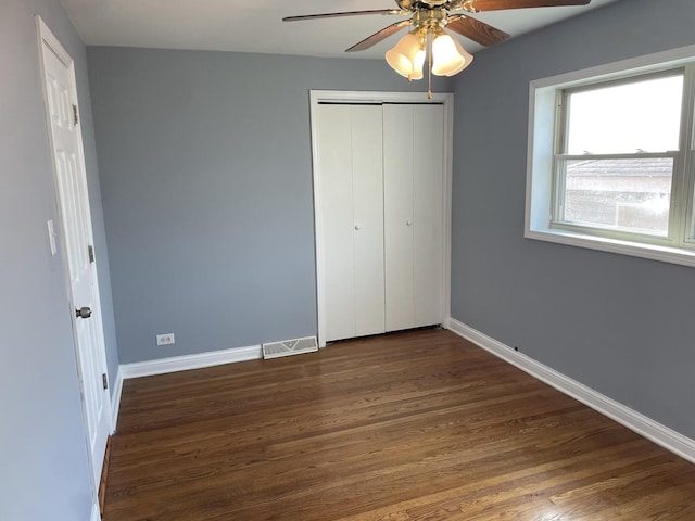 unfurnished bedroom with ceiling fan, a closet, and dark wood-type flooring