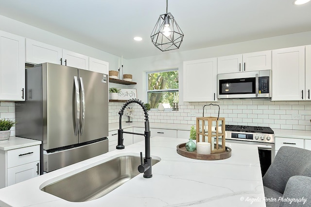 kitchen with white cabinets, hanging light fixtures, decorative backsplash, appliances with stainless steel finishes, and light stone counters