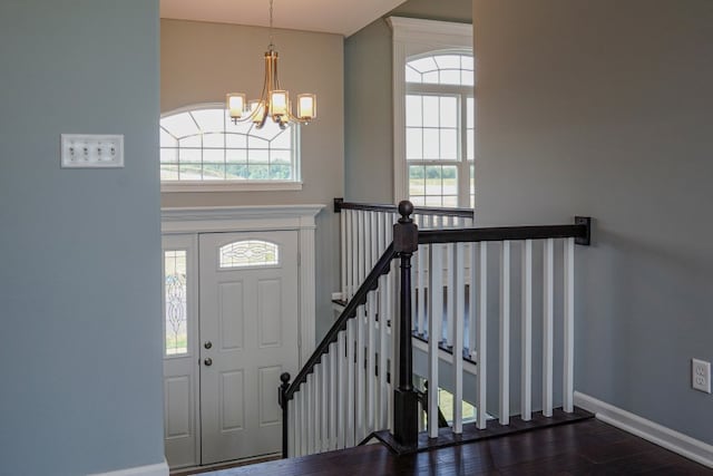 foyer entrance featuring a high ceiling, dark wood-style flooring, an inviting chandelier, and baseboards