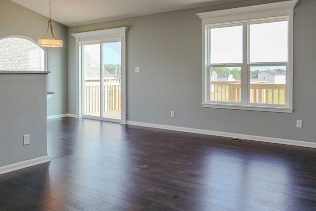 unfurnished room with lofted ceiling, visible vents, dark wood finished floors, and baseboards