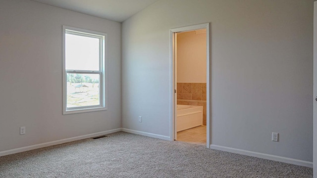 spare room with light carpet, visible vents, baseboards, and lofted ceiling