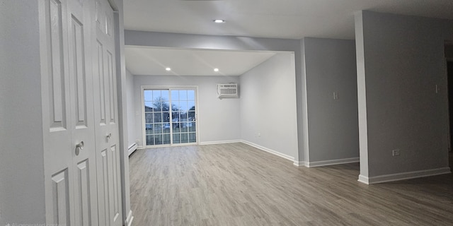 unfurnished room featuring hardwood / wood-style floors, a wall mounted AC, and a baseboard heating unit