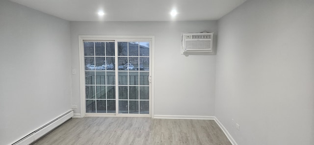 unfurnished room featuring a wall mounted air conditioner, baseboard heating, and light hardwood / wood-style flooring