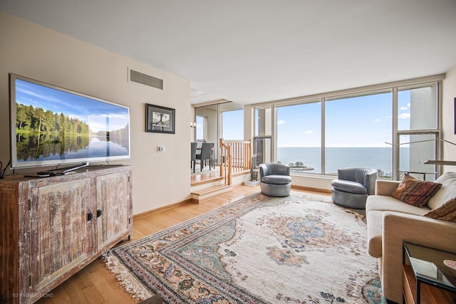 living room featuring a water view and light hardwood / wood-style flooring